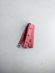 Pink tailor's measuring tape folded and isolated on a white background. Sewing, craft, and body measurement concept.