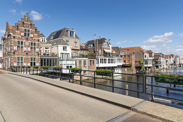 Charming traditional Dutch houses line the historic canal in Gorinchem, adorned with flower boxes, under a bright blue sky.
