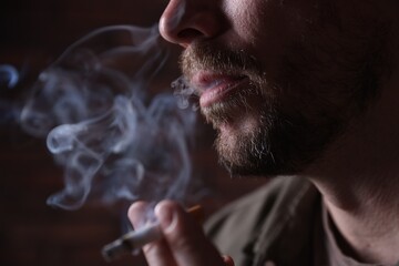 Man smoking cigarette on blurred background, closeup