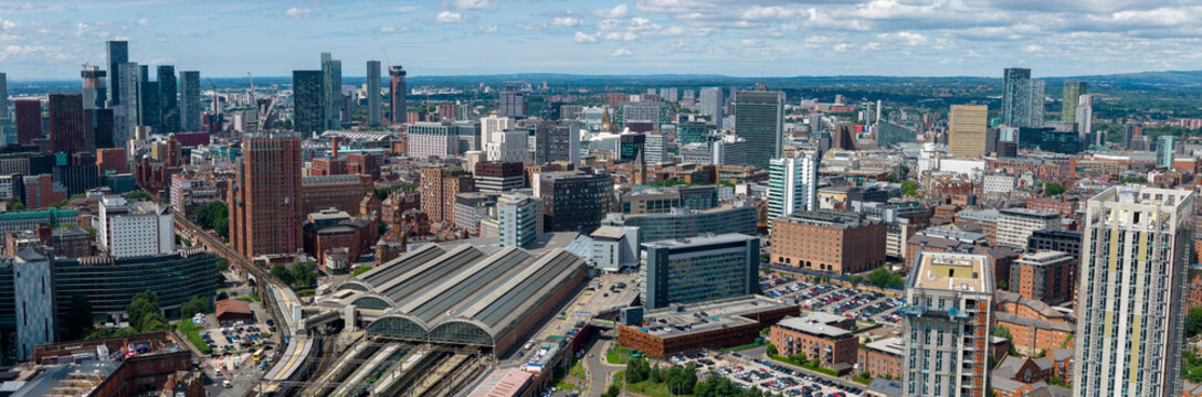 Elevated aerial panorama of Manchester cityscape featuring Picadilly train station and cluster of high-rise buildings. 