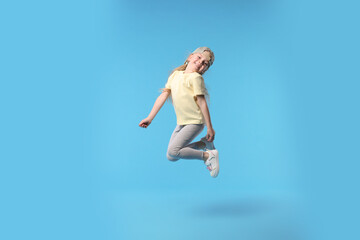 Obraz premium Cute little girl dancing on light blue background