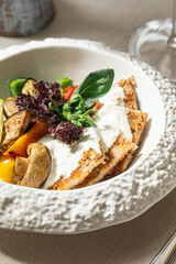 Turkey schnitzel with white sauce and grilled vegetables on white plate