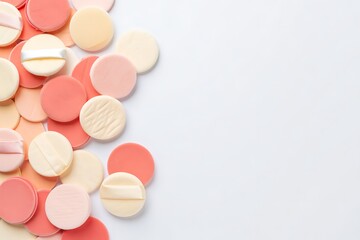 Obraz premium A Beautiful Assortment of Round Makeup Sponges in Various Shades of Pink Orange and Yellow Scattered Across a White Background Creating a Visually Pleasing Composition of Beauty Products