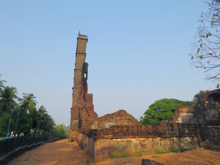 Ruins of the Church of St. Augustine tower in Old Goa, India, with weathered laterite brick walls...