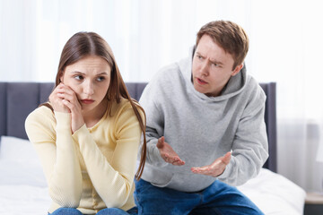 Woman and man having quarrel on bed at home