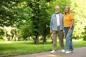 Obraz premium Lovely senior couple walking together in park, space for text