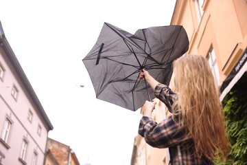 Woman with broken umbrella outdoors, low angle view