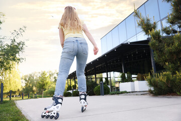 Young woman roller skating outdoors, back view