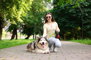 Happy woman with her cute Alaskan malamute dog in park