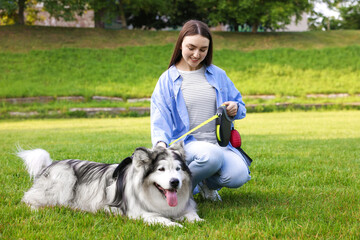 Happy woman with her cute Alaskan malamute dog on green grass outdoors