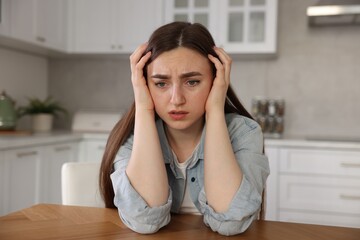 Woman suffering from paranoia at table in kitchen