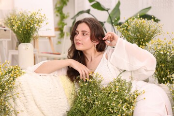 Portrait of beautiful woman with chamomile flowers indoors