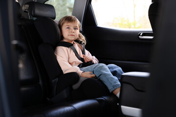 Little girl sitting in child safety seat inside car