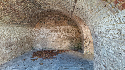 Obraz premium Ancient Brick Arched Structure with Weathered Surface and Fallen Leaves