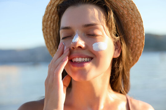 Beautiful young woman with sun cream on face. Girl applying sunscreen lotion on skin.Skin care. Sun protection. Suntan