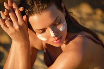 Beautiful young woman with sun cream on face. Girl applying sunscreen lotion on skin.Skin care. Sun...