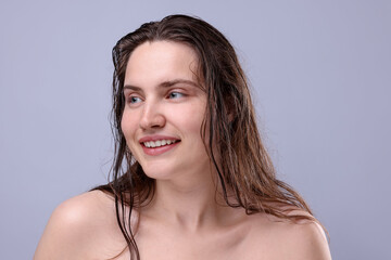 Smiling woman with natural skin complexion on grey background, closeup