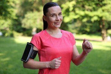Sporty woman with armband running in park