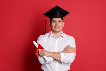 Happy student with diploma after graduation on red background