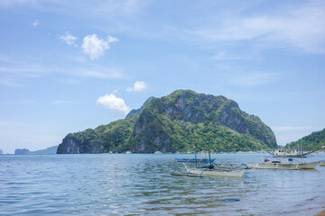 Traditional Filipino boats Floating in El Nido Bay with Limestone Island Backdrop, Palawan. Idyllic...
