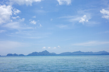 A peaceful seascape capturing the gentle gradation of blues from the clear ocean to the expansive sky, with silhouettes of distant tropical islands with Distant Tropical Islands, Palawan, Philippines