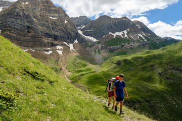 Fototapeta premium Hikers backpacking up a hill with mountains in the background.