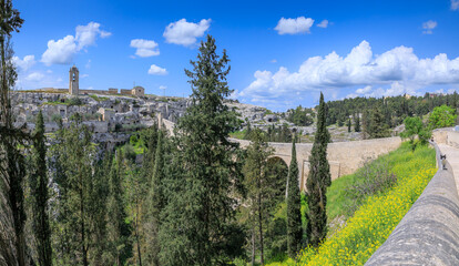 View of ravine with the Aqueduct Bridge from Roman times and rocky houses in Gravina in Puglia town, southern Italy.