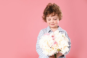 Cute little boy with bouquet of beautiful peonies on pink background. Space for text