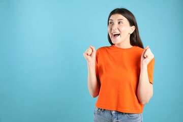 Portrait of surprised woman on light blue background, space for text