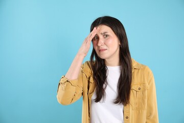 Portrait of confused woman on light blue background, space for text