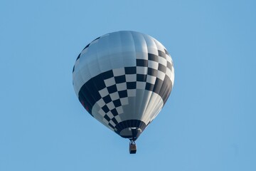 Black and white hot air balloon flying in blue sky