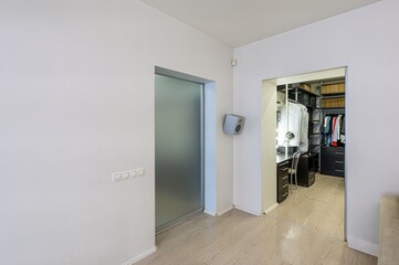 Bright interior featuring a frosted glass door and an open walk-in closet with shelving and a vanity desk