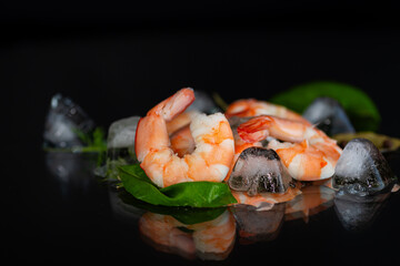 Boiled shrimp with ice and spices on a black background