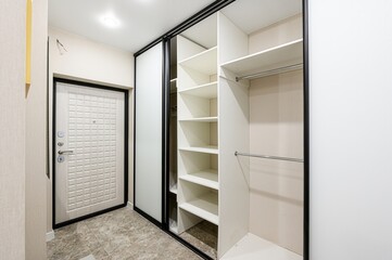 Modern entryway featuring a white door, sliding closet with open shelves, and neutral decor