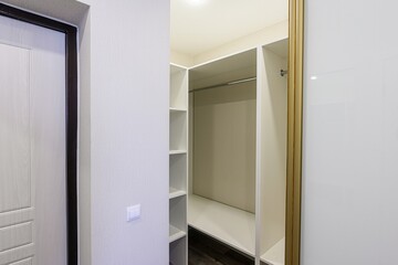 well-lit interior showcasing a white walk-in closet with open shelving, a hanging rod, and a glossy...