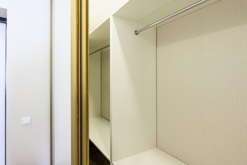 partial view of an open, organized closet with shelves and a hanging rod. The closet features...