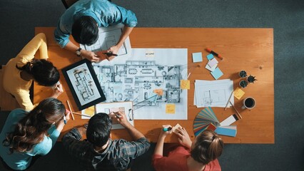Top down aerial view of smart engineer looking at blueprint at meeting room. Skilled architect team...