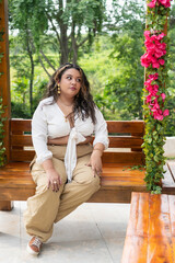Fashion model sitting on wooden bench in garden setting