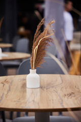 The decor on the table of an outdoor cafe. A vase with a spikelet