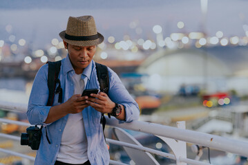 Tourist asian man backpacker enjoying solo travel vacation using cell phone on the ship. Tourism...