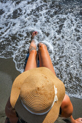 Woman sunbathing on sandy beach in swimsuit and straw hat, Ulcinj, Montenegro