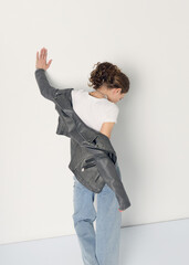 a woman dressed in accordance with fashion trends, in a leather jacket and a white top poses...