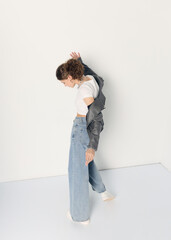 a woman dressed in accordance with fashion trends, in a leather jacket and a white top poses...