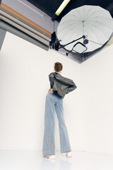 A stylishly dressed woman poses in a photo studio on a white background, the concept of photo...