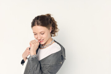 a woman dressed in accordance with fashion trends, in a leather jacket and a white top poses...