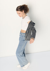 a woman dressed in accordance with fashion trends, in a leather jacket and a white top poses...