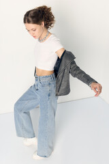a woman dressed in accordance with fashion trends, in a leather jacket and a white top poses...