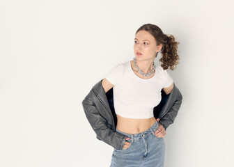 a woman dressed in accordance with fashion trends, in a leather jacket and a white top poses...