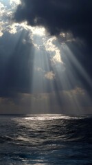 Sunlight beams through storm clouds over the ocean creating atmospheric scene