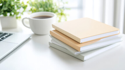 Minimalist workspace with neutral notebooks, laptop, and coffee cup in bright daylight